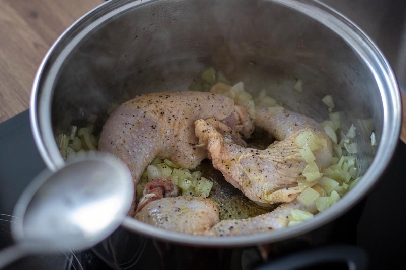 Chicken legs, onion and garlic in pan