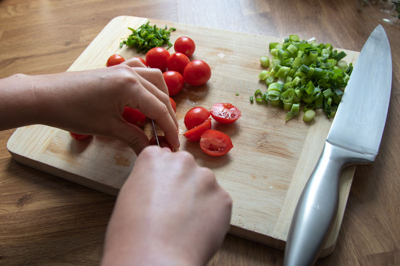 Chopping the tomatoes, also shows chopped spring onions and chives