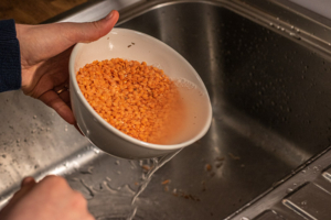 Rinsing lentils in a bowl over the kitchen sink