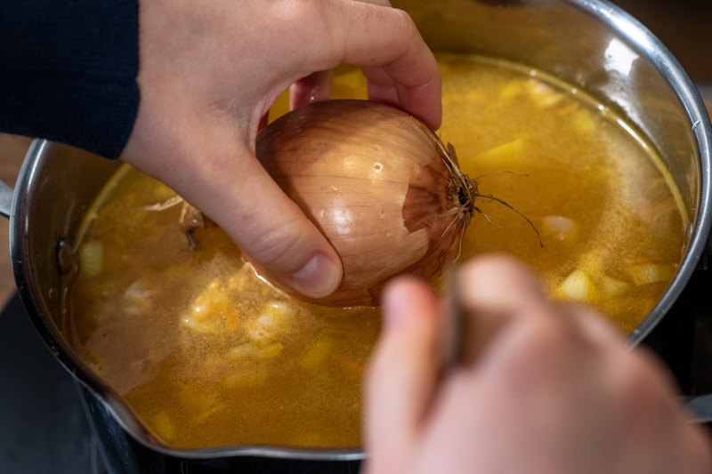 A whole onion being added to the soup
