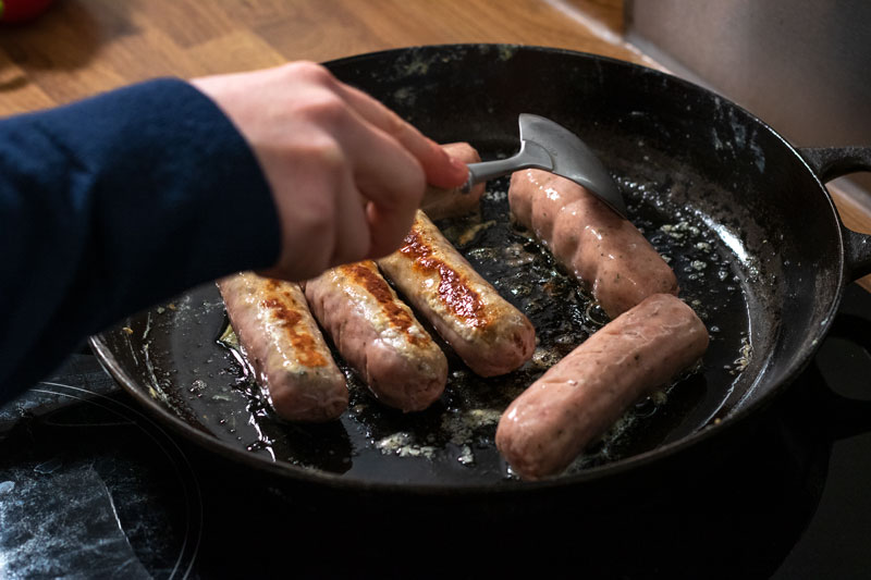Sausages being fried in a pan