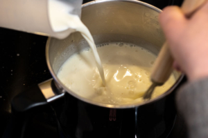 Milk being poured in to a saucepan while making a white sauce